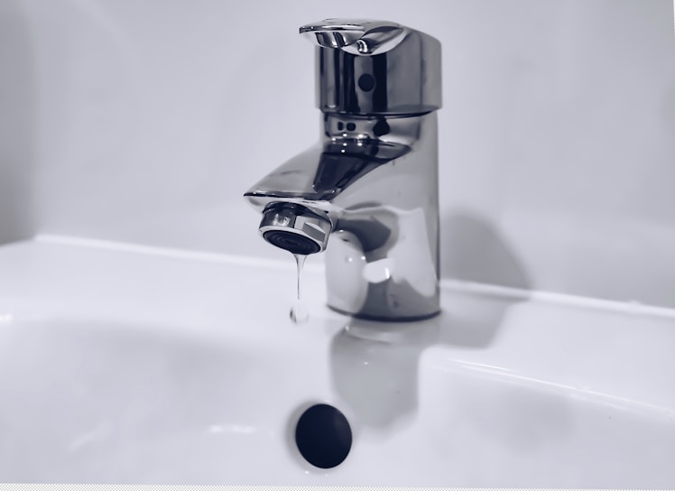 A handyman fixing a leaky faucet in a bright, modern kitchen.