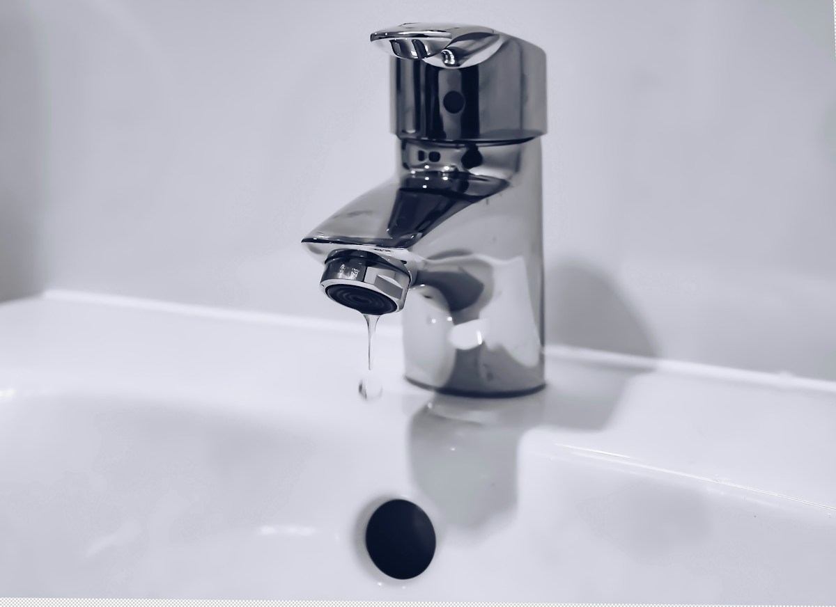 Chrome basin tap with a drip forming