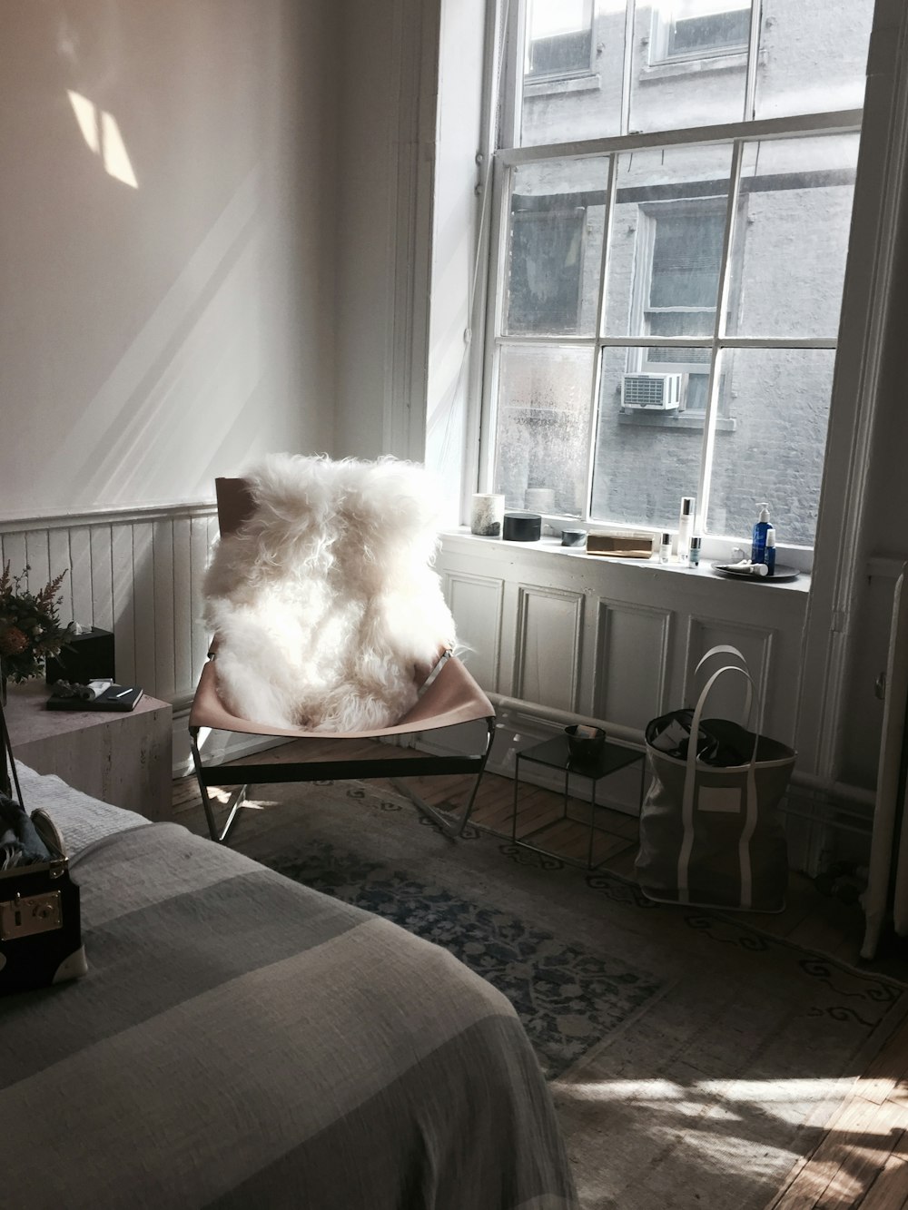 white fur chair cover on brown chair beside glass window