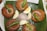 Five golden-brown, crispy cutlets are arranged on a green banana leaf. Each cutlet is topped with a slice of raw onion and a whole green chili. Slices of hard-boiled eggs and additional raw onion are placed in the center for garnish.