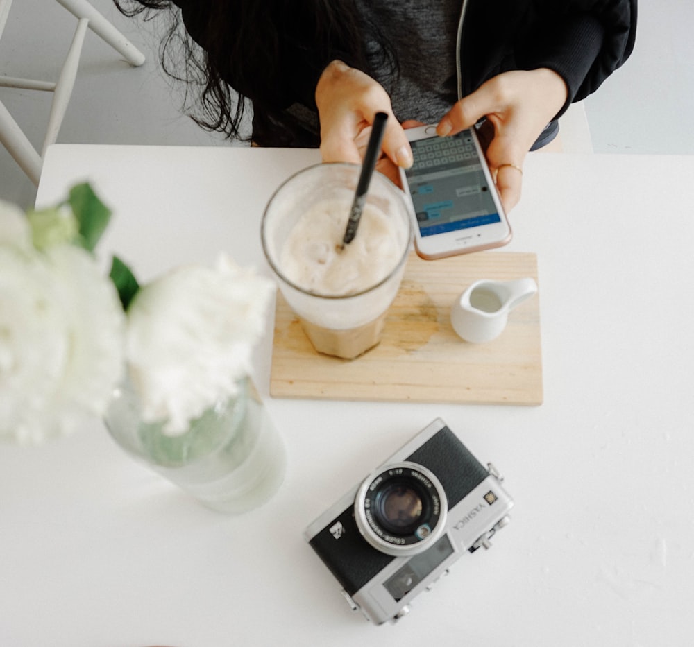 person sitting using iPhone near table with camera on table