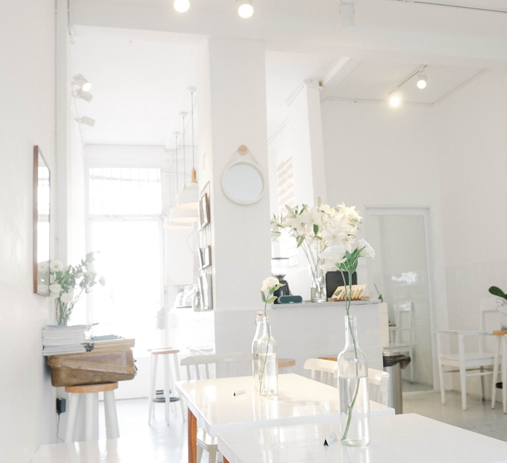 fleur à pétales blancs dans une bouteille en verre transparent sur la table