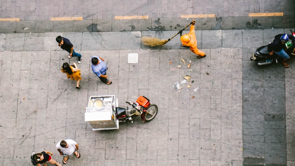 people walking near man sweeping on road during daytime