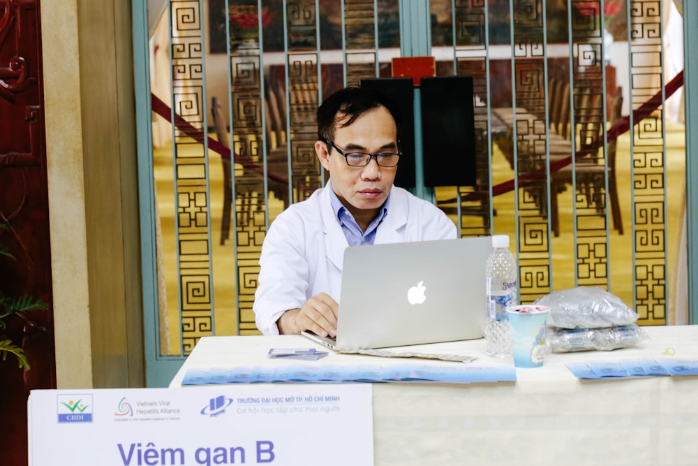 man using silver MacBook near blue metal gate