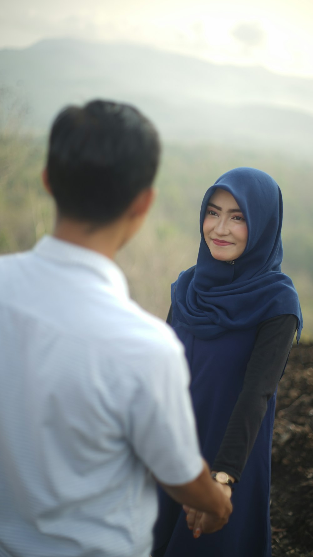woman wearing hijab smiling in front of man