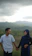 Smiling couple standing in front of their new villa with lush green hills in the background.