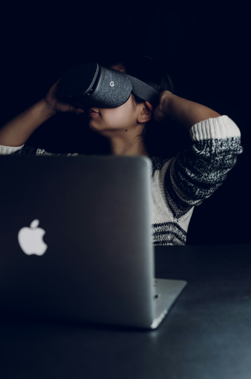 woman wearing black virtual reality headset facing on MacBook