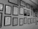 A wall adorned with an array of framed certificates and diplomas, meticulously organized in several rows. The frames are of uniform dark color, contributing to a professional and orderly appearance.