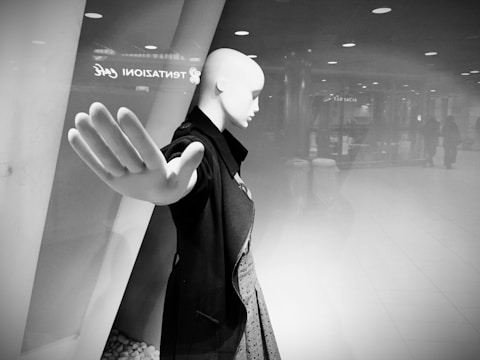 Mannequin displaying a coat inside a dimly lit warehouse setting.