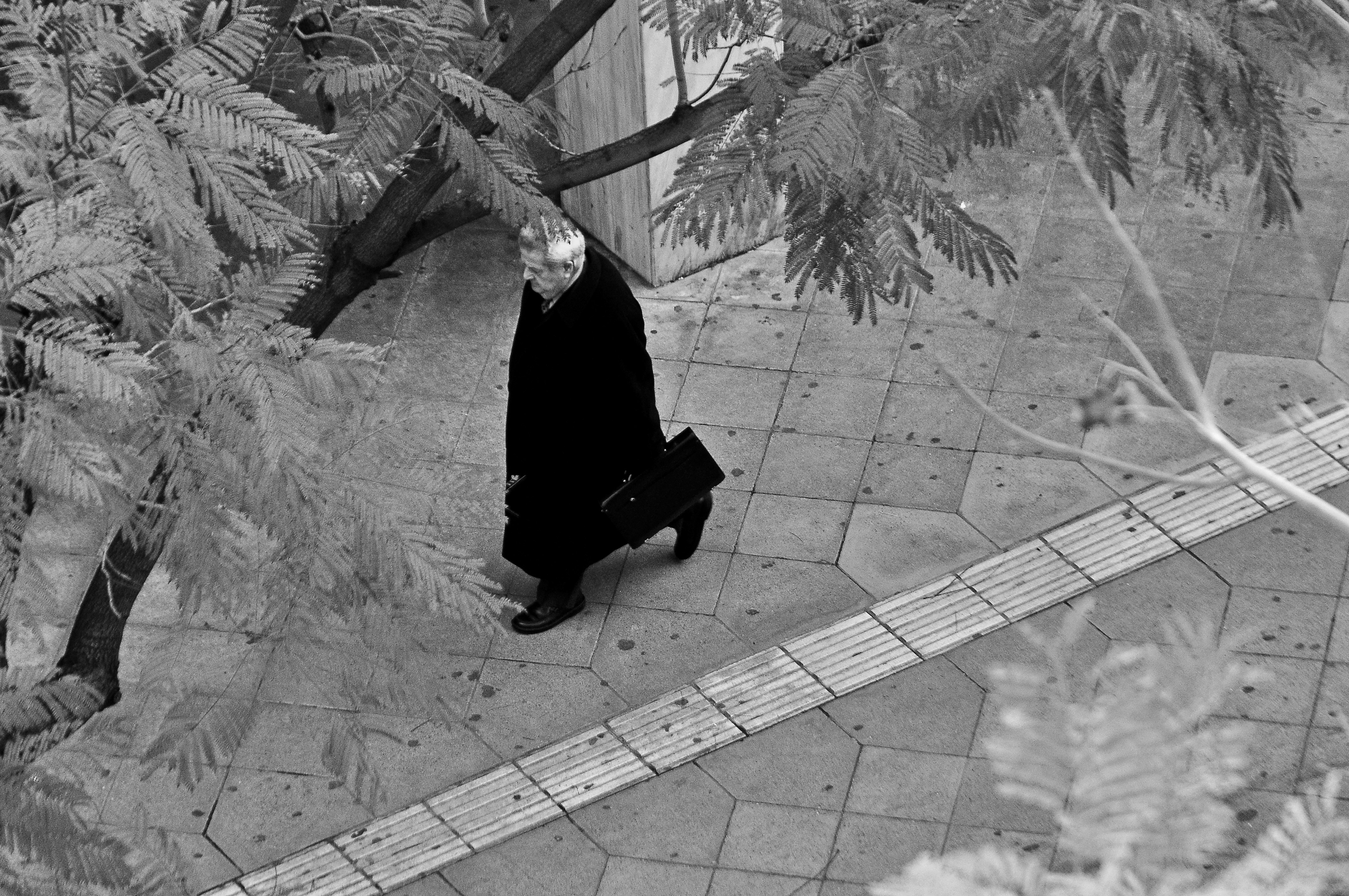 grayscale of man walking on street
