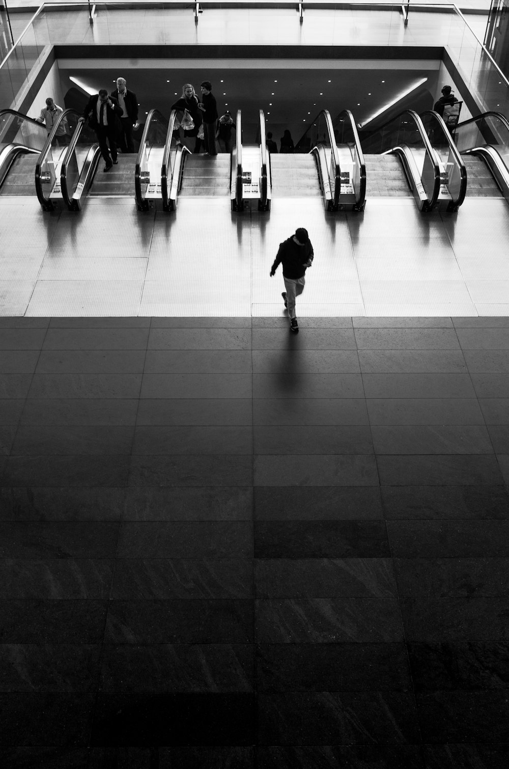 grayscale photography of man walking near escalator