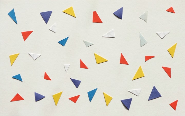 A variety of purple, blue, red, yellow, and white paper triangles, strewn about.