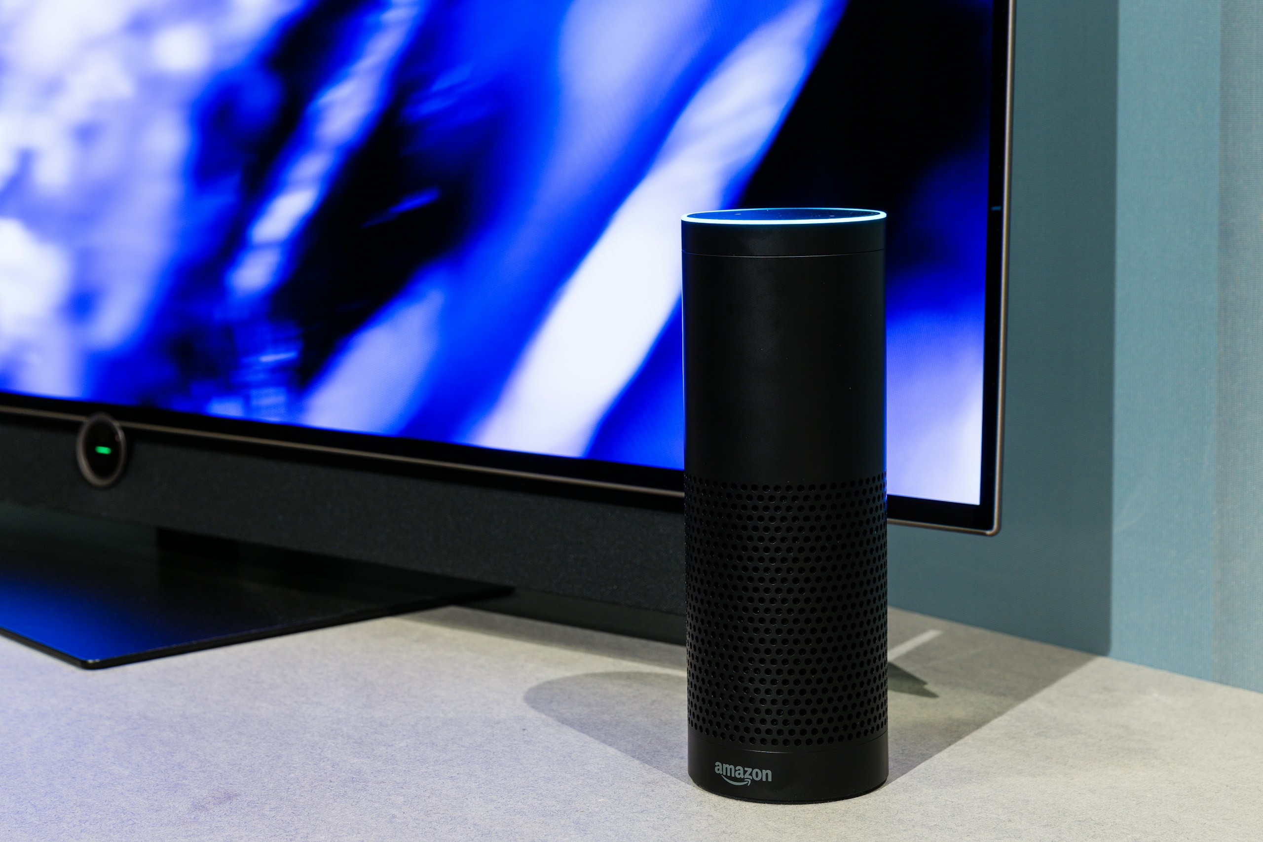 black amazon echo smart speaker near turned-on flat screen TV