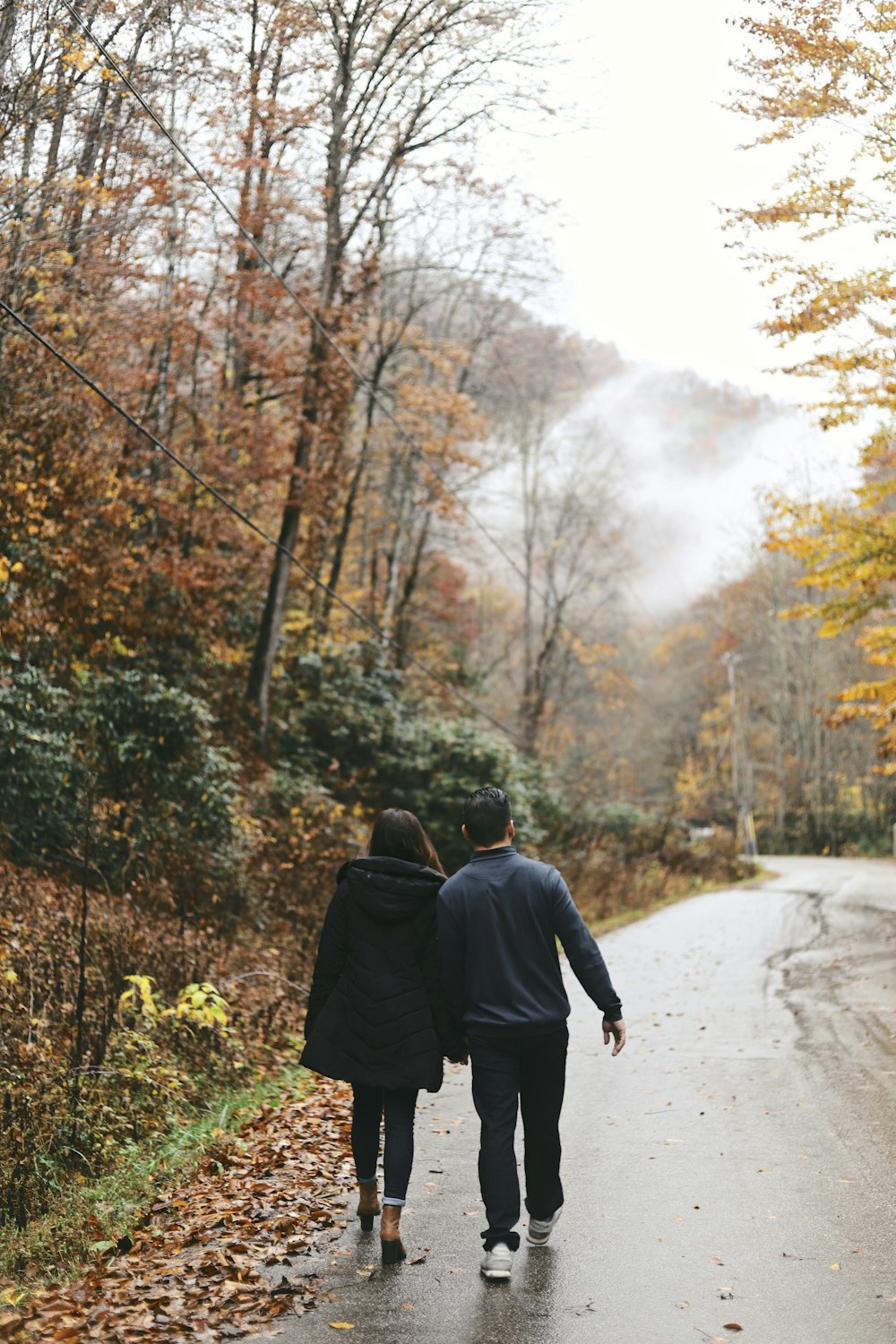 couple walking at the road between trees