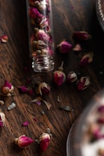Close-up of natural oud wood and rose petals arranged artistically on a dark surface.