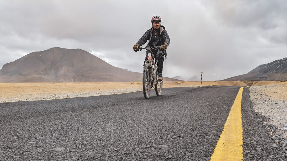 man riding bicycle on asphalt road during daytime