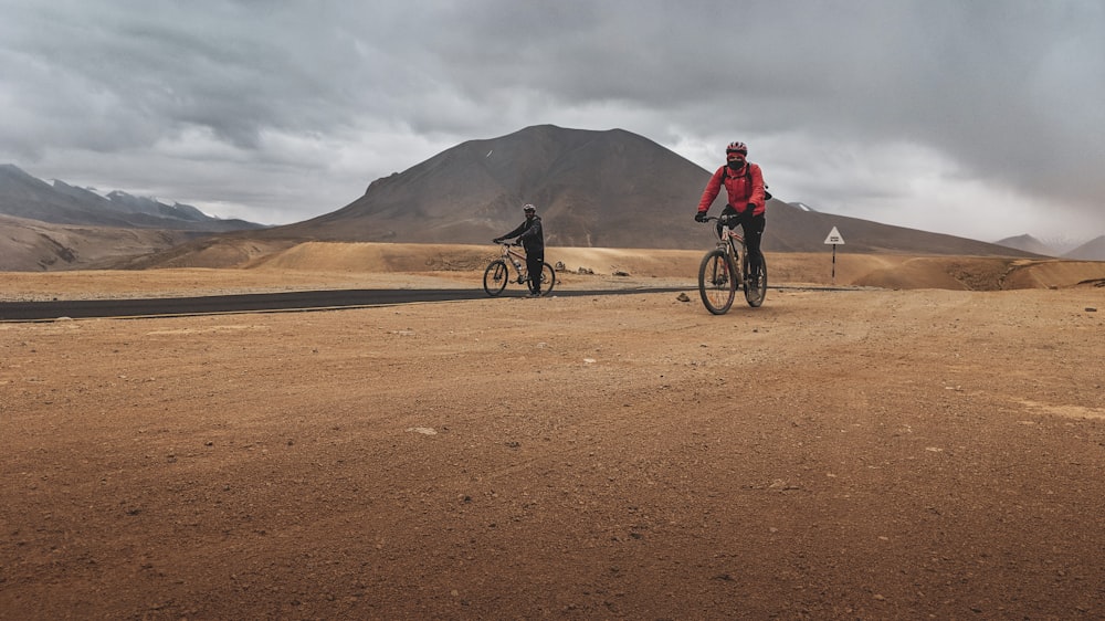 two men riding bicycle on dirt track during daytime