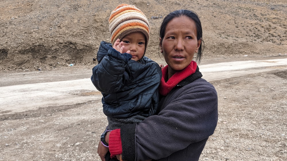 woman carrying boy beside road