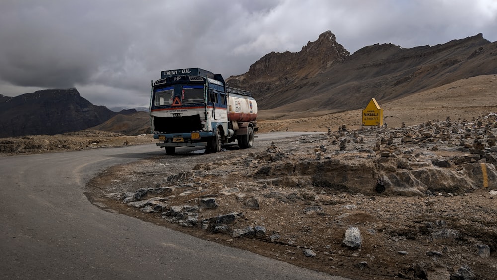 white-and-blue tanker truck running on curved road during daytime