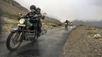 Riders wearing helmets and protective gear preparing their motorcycles before a mountain journey.