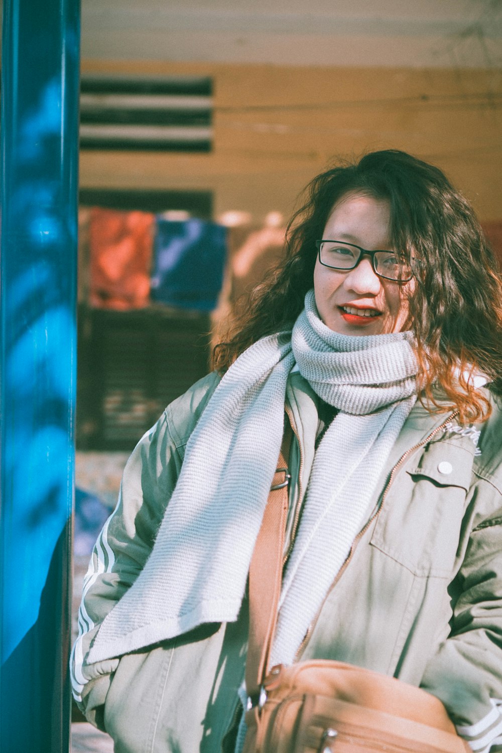 woman wearing gray coat, scarf and brown leather crossbody bag during daytime