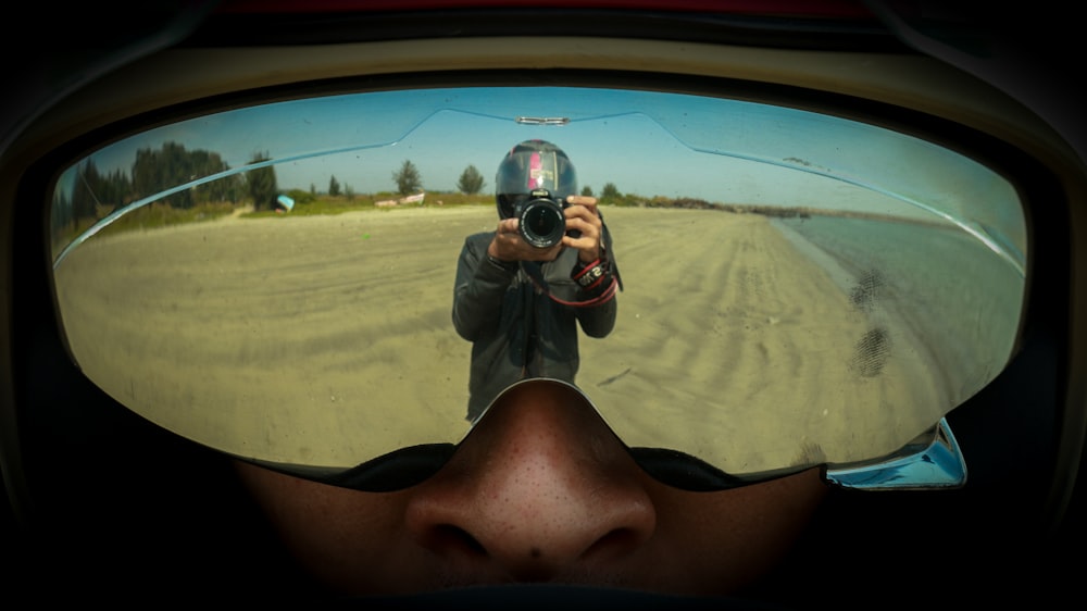fotografia de reflexão da pessoa segurando a câmera DSLR
