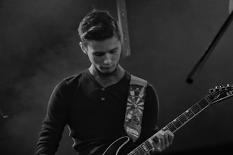 Black and white shot of Ilker Karacam playing guitar with intense focus