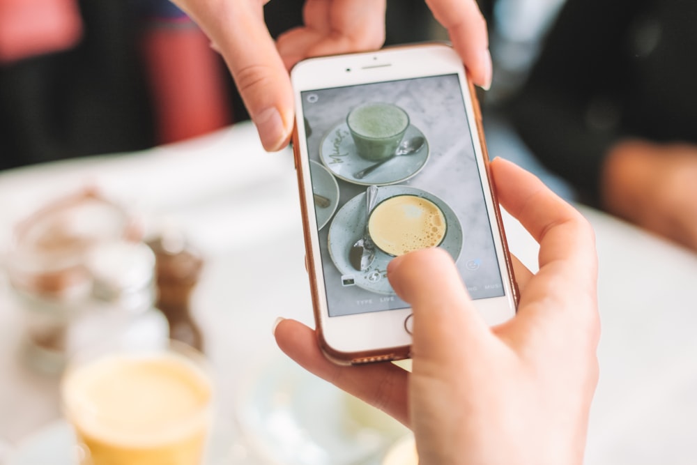 person taking picture of two teacups