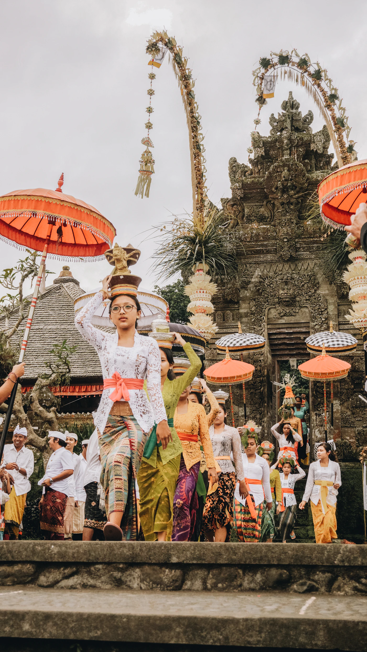 Balinese women in traditional dress carrying offerings on their heads during a temple ceremony