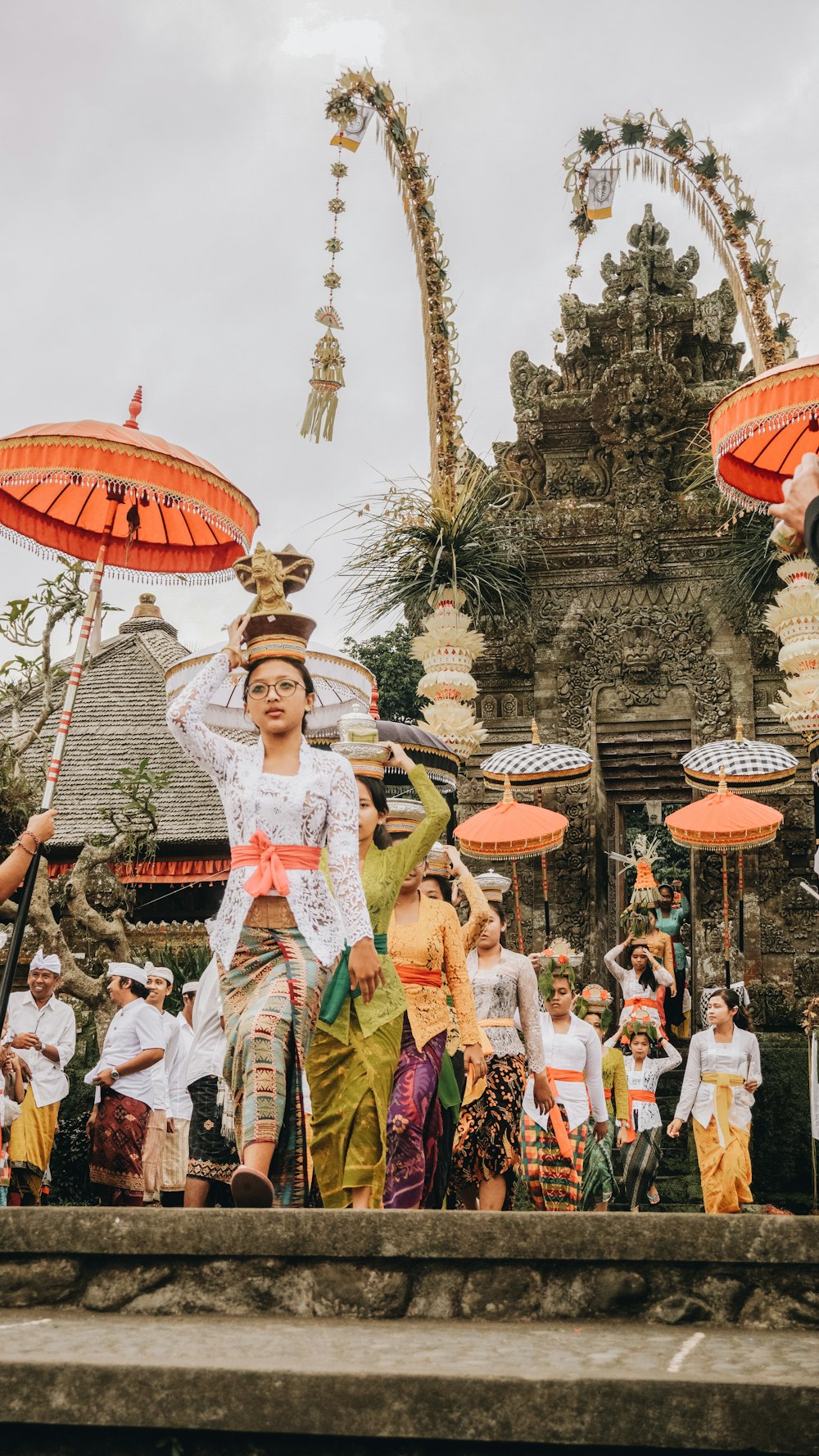 women in traditional dress with flower pots on head during daytime