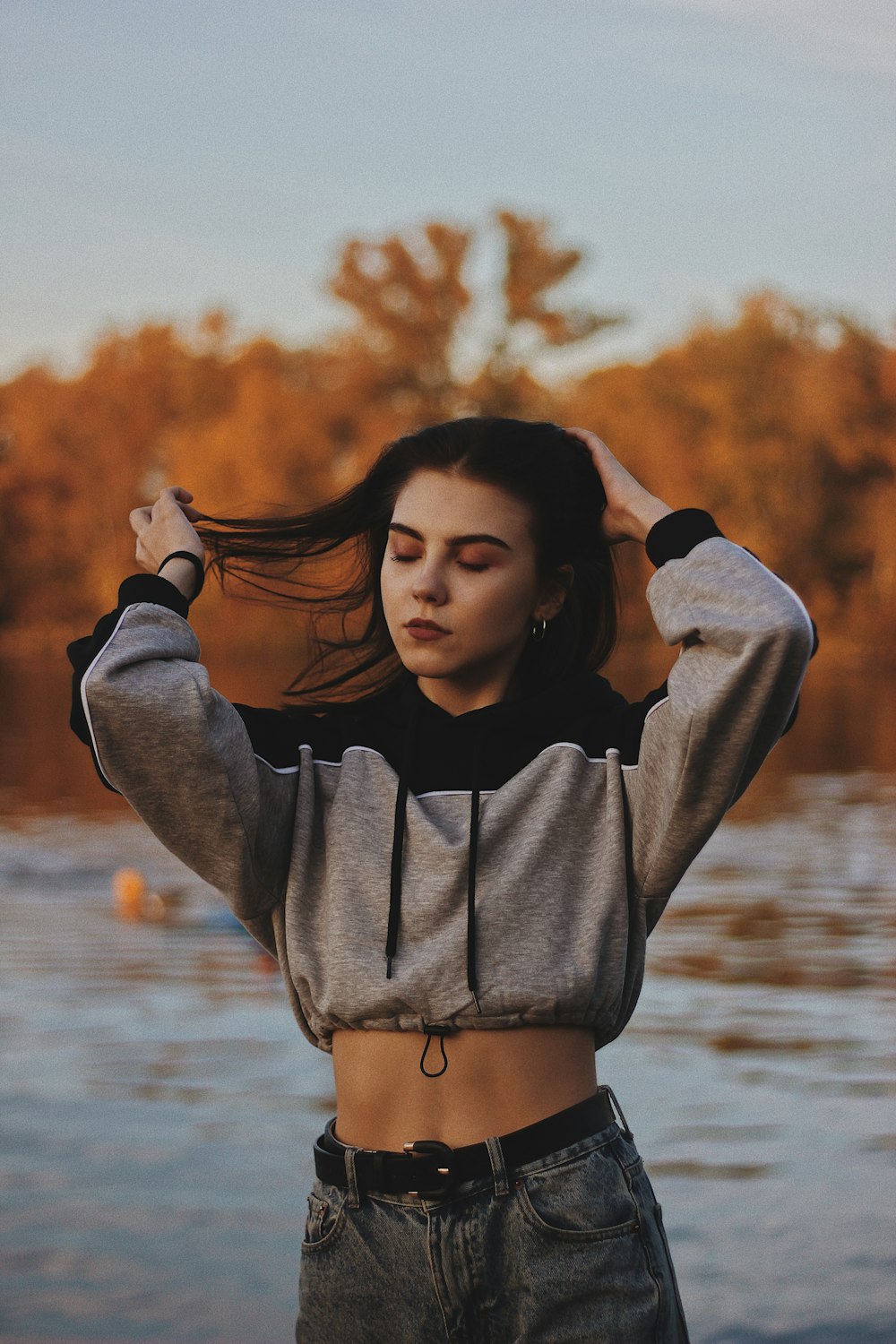 woman wearing gray-and-black crop hoodie and blue denim bottoms during daytime