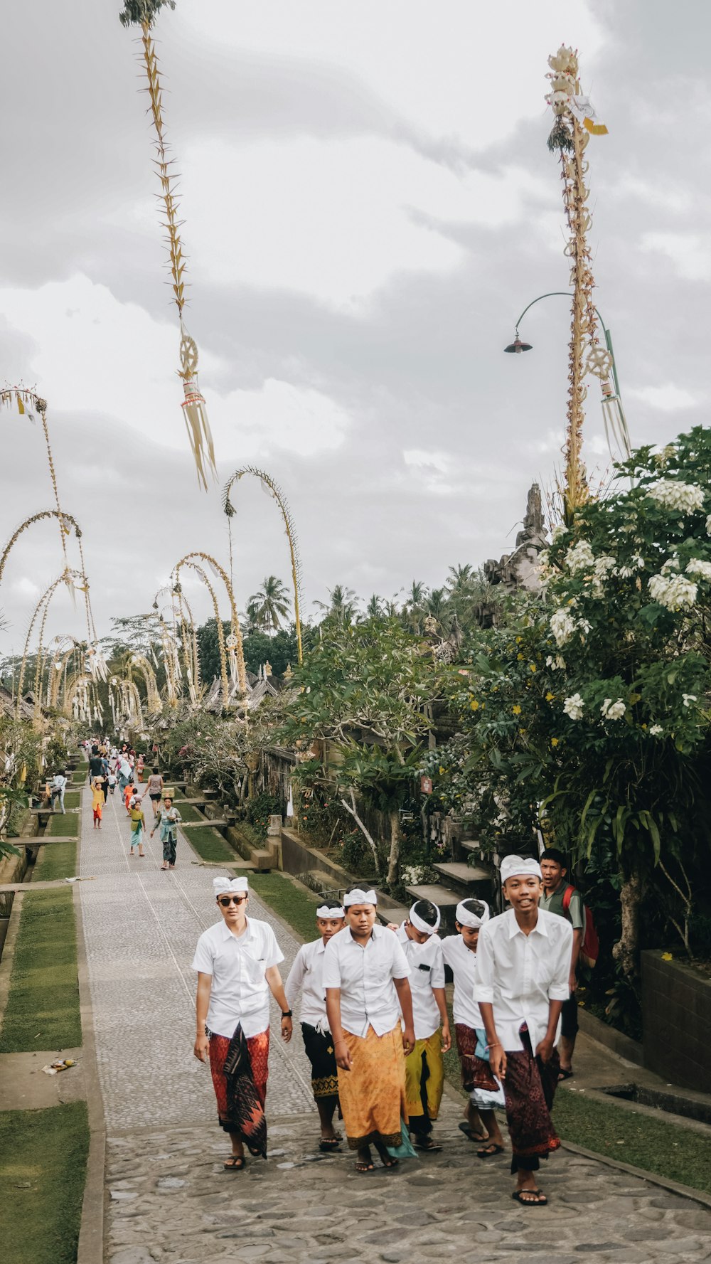 group of men walking at middle of walkway beside flowers