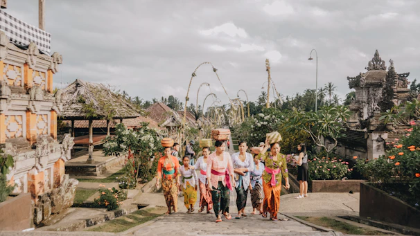 A smiling guide leading a small group past colorful Balinese temple carvings.
