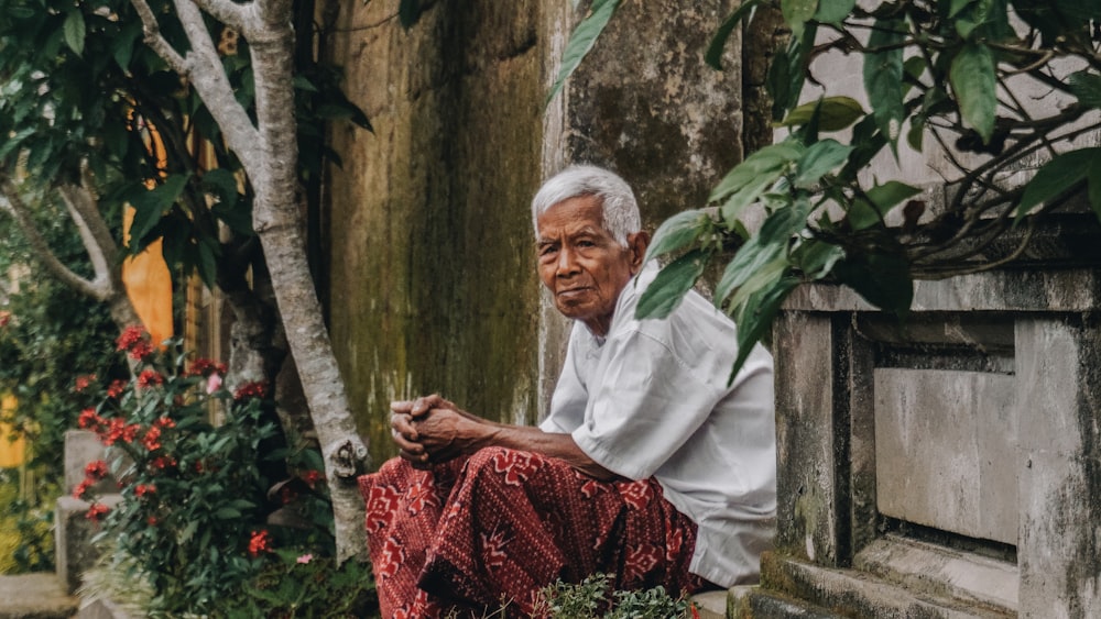 man siting beside wall near trees