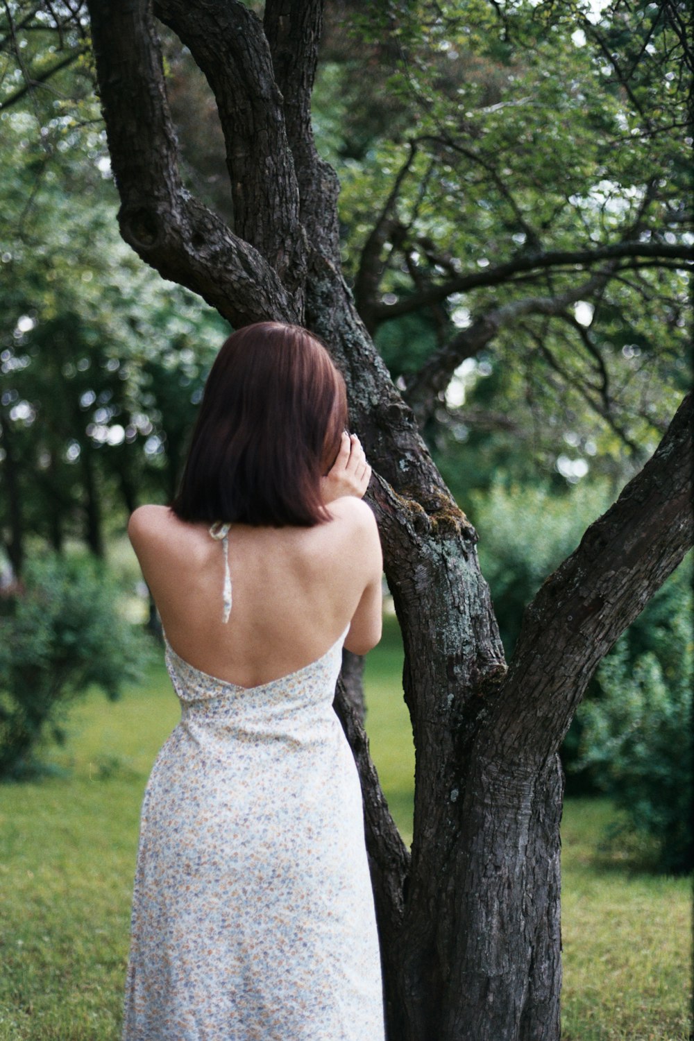 woman in white halter dress looking at tree