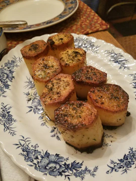 Golden-brown baked sweet potatoes resting on a ceramic plate with a sprinkle of herbs.