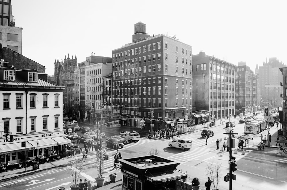 grayscale photography of cars on road between building