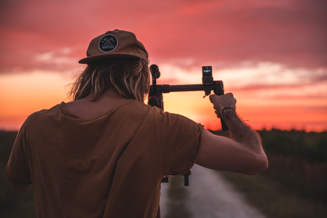 man holding camera with stabilizer during golden hour