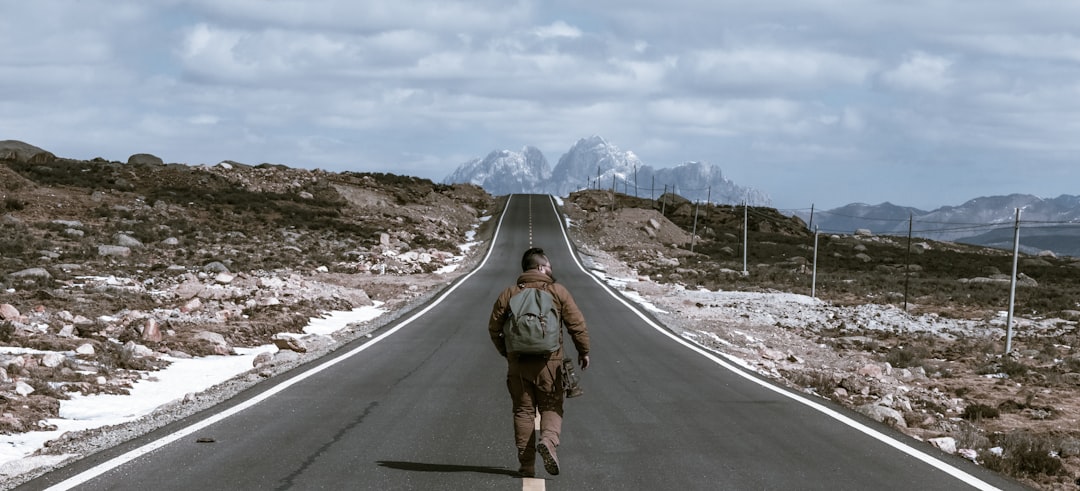 man walking on the center of road during daytime