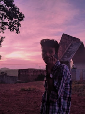 A friendly technician answering a phone call in front of a roofing truck at sunset.