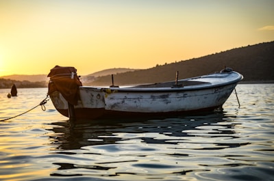 A stunning sunset backdrop with a small fishing boat gently drifting on the water.