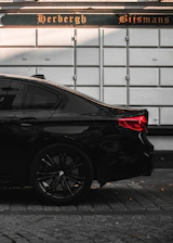 A sleek black taxi parked in front of a charming Kortrijk street at dusk.