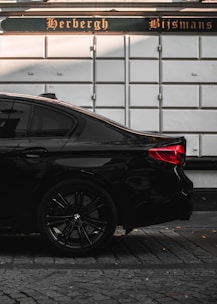 A sleek black taxi waiting outside Eindhoven Airport terminal with luggage in the trunk.