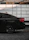 A sleek black car waiting outside Brussels Airport with a clear sign showing the passenger's name.
