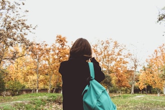 A student wearing a backpack standing on a Canadian university campus during fall.