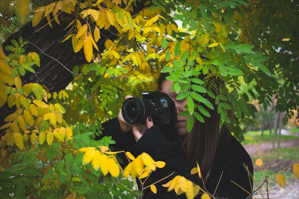 Frau fotografiert neben Baum