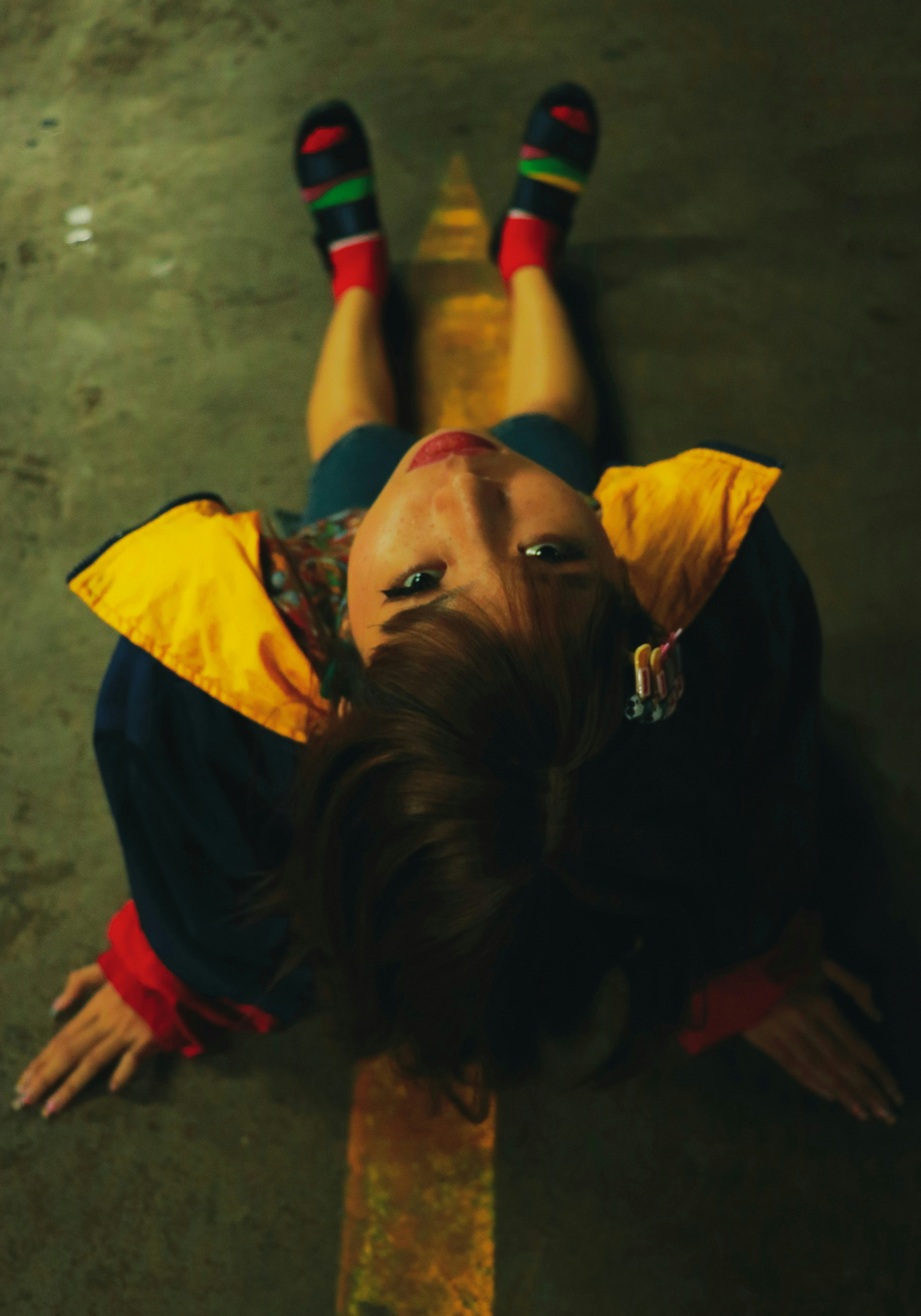 Gadis duduk di lantai mengenakan jaket kuning dan hitam