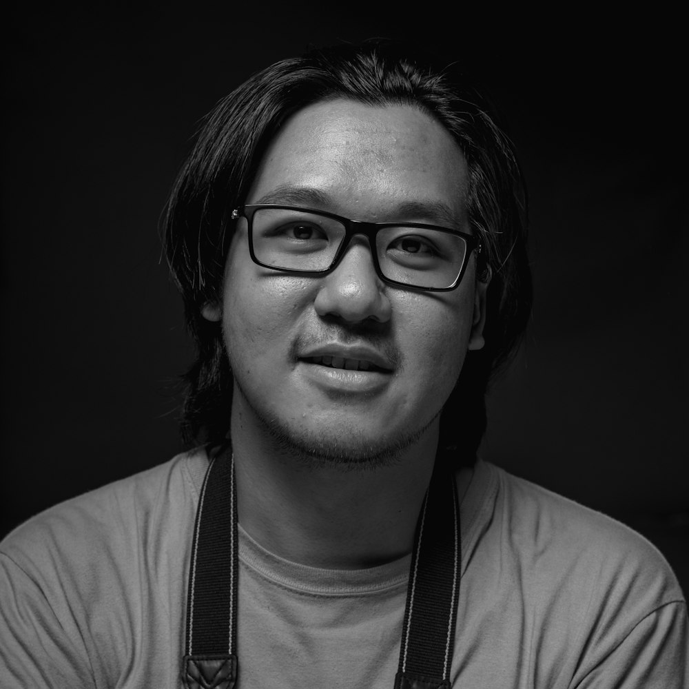 grayscale photography of man wearing eyeglasses and crew-neck shirt