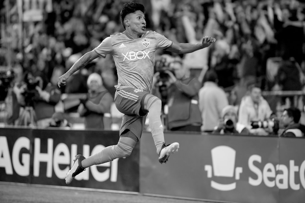 Foto en escala de grises de un hombre jugando al fútbol