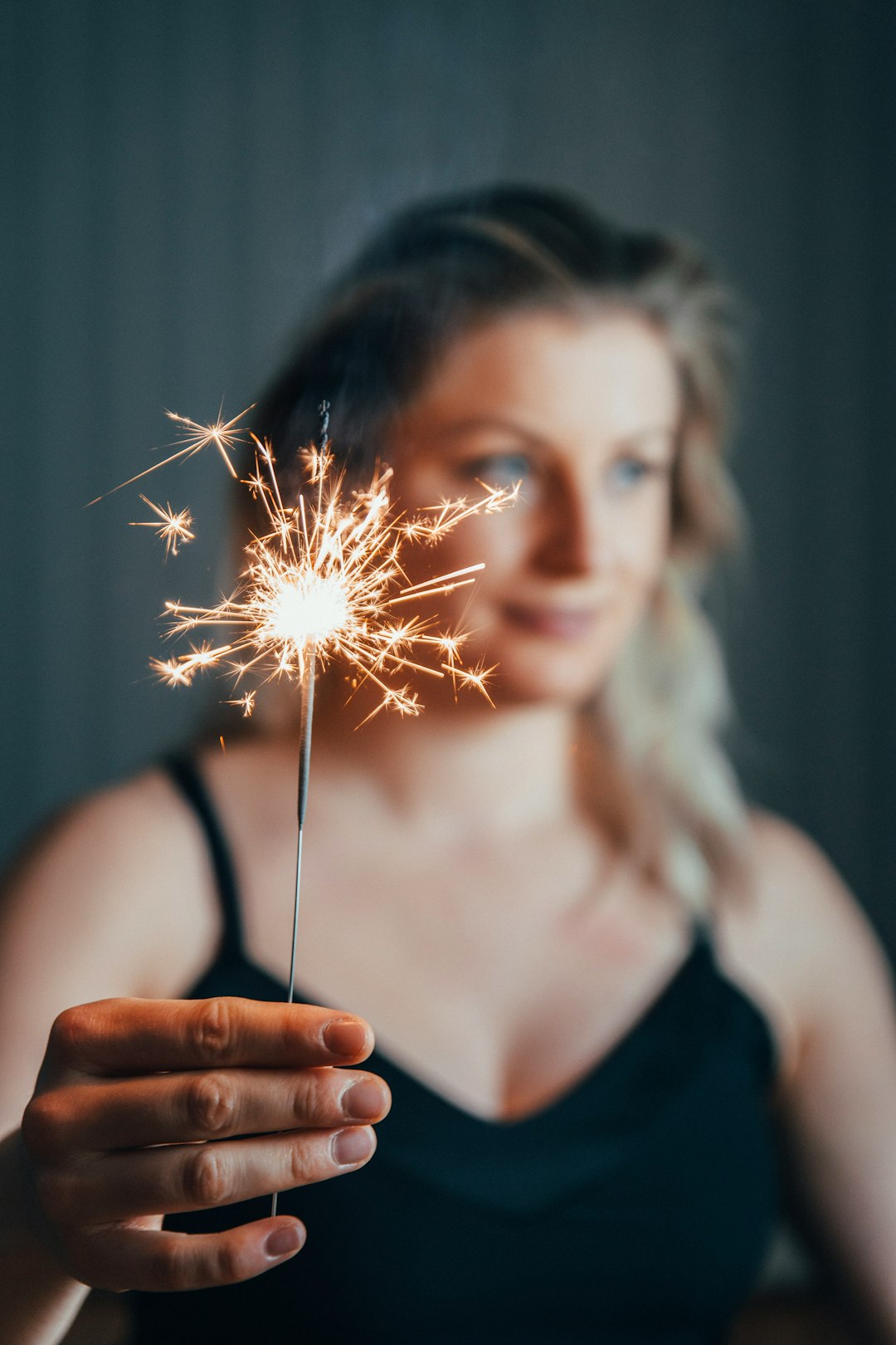 woman wearing black spaghetti strap blouse holding fireworks